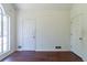 Neutral room featuring a double door, a white door with a gold handle, wood flooring, and natural light at 101 Valleydale Dr, Stockbridge, GA 30281