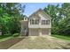 Charming two-story home features a two-car garage, light siding, green trees and neatly landscaped front yard at 1303 Flat Shoals Rd, Atlanta, GA 30349