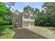Charming two-story home features a two-car garage, light siding, green trees and neatly landscaped front yard at 1303 Flat Shoals Rd, Atlanta, GA 30349