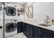 Convenient laundry room with stacked washer and dryer, granite countertop, sink, and storage cabinets at 3039 Malbec Vly, Acworth, GA 30101