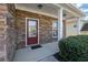 Close-up of a stone-clad entryway, showcasing a red front door and manicured bushes at 679 Barley Hill Ln, Sugar Hill, GA 30518
