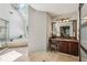 Relaxing bathroom featuring a soaking tub, glass-enclosed shower, vanity, and skylight for natural lighting at 12370 Preserve Ln, Johns Creek, GA 30005