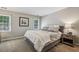 Neutral bedroom featuring a bed with an upholstered headboard and side table with a lamp at 12370 Preserve Ln, Johns Creek, GA 30005
