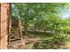 Landscaped backyard with stairs leading to an elevated deck area with ample greenery and shade at 745 Abbotts Mill Ct, Johns Creek, GA 30097