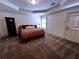 Spacious bedroom with a large bed, neutral carpeting, tray ceiling, and plantation shutters for natural light at 9390 Colonnade Trl, Johns Creek, GA 30022