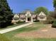 Stately brick home features manicured lawn, mature trees, and a welcoming facade with classic architectural details at 9390 Colonnade Trl, Johns Creek, GA 30022