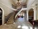 Bright foyer showcasing curved staircase, travertine floors, arched entryway, and an open view to the living room at 9390 Colonnade Trl, Johns Creek, GA 30022