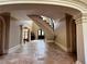 Spacious foyer featuring travertine floors, arched doorways, ornate trim, and a curved staircase leading to upper level at 9390 Colonnade Trl, Johns Creek, GA 30022
