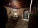 Cozy wine cellar with stone walls, wood ceiling, table, seating, and wrought iron gate at 9390 Colonnade Trl, Johns Creek, GA 30022