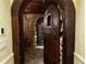 Arched doorway to the stone-walled wine cellar with custom wood door and wrought iron details at 9390 Colonnade Trl, Johns Creek, GA 30022