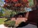 View of the yard and home exterior, with brick retaining wall, featuring mature trees and lush landscaping at 9390 Colonnade Trl, Johns Creek, GA 30022