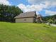 A view of the back of the home with a large grassy backyard under a sunny sky at 1750 Stone Meadow Rd, Lithonia, GA 30058