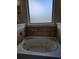 Close up of a ceramic bathtub with tiled backsplash and a window for natural light at 1750 Stone Meadow Rd, Lithonia, GA 30058