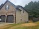 Side view of a brick home with a two car garage, next to green space at 1750 Stone Meadow Rd, Lithonia, GA 30058