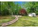 Lush backyard featuring a stone pathway, fire pit, and storage shed surrounded by mature trees at 1953 Windcrest Sw Dr, Lilburn, GA 30047