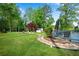 Expansive backyard with fire pit, stone path, wooden deck, storage shed, and mature trees at 1953 Windcrest Sw Dr, Lilburn, GA 30047