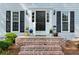 Inviting front entrance with brick steps, black door with sidelights and decorative planters at 1953 Windcrest Sw Dr, Lilburn, GA 30047