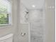Walk-in shower boasts marbled tile and a rainfall showerhead with exterior window at 1953 Windcrest Sw Dr, Lilburn, GA 30047