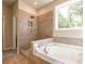 Modern bathroom with a tiled walk-in shower and a soaking tub near a window at 4082 Adler Cir, Buford, GA 30519