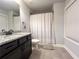 Well-lit bathroom featuring a granite countertop vanity and shower-tub with patterned curtain at 552 Warrenton Run Dr, Sugar Hill, GA 30518