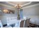 Stylish dining room featuring a modern chandelier, wainscoting, and a chic white table setting at 552 Warrenton Run Dr, Sugar Hill, GA 30518