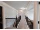 Upstairs hallway with carpet, decorative iron railing, and multiple light fixtures at 552 Warrenton Run Dr, Sugar Hill, GA 30518
