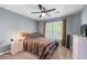 Cozy bedroom with ceiling fan, natural light from a window, and colorful bedding; carpeted flooring throughout at 1035 Bridle Path Dr, Lawrenceville, GA 30045