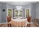 Bright dining area with chandelier, table set for tea, surrounded by windows overlooking a lush landscape at 1035 Bridle Path Dr, Lawrenceville, GA 30045