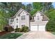 Two-story stucco home with a two-car garage and mature trees in front at 1035 Bridle Path Dr, Lawrenceville, GA 30045