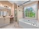 Bright main bathroom featuring a soaking tub, glass shower, vanity with seating area, and large window at 1035 Bridle Path Dr, Lawrenceville, GA 30045
