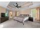 Large main bedroom with tray ceiling, ceiling fan, carpet floors, windows, and a seating area at 1035 Bridle Path Dr, Lawrenceville, GA 30045