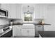 Modern kitchen featuring white cabinets, a farmhouse sink, stainless steel appliances, and black countertops at 1817 Bedfordshire Dr, Decatur, GA 30033
