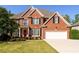 Stately two-story brick home featuring a well-manicured lawn, attached garage and a classic red front door at 2553 Twilight Vw, Snellville, GA 30078