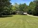 Charming exterior view of the home surrounded by a lush green lawn and mature trees at 999 Grassdale Rd, Cartersville, GA 30121