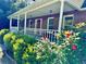 A brick home with a charming front porch, surrounded by lush greenery and colorful flowers at 999 Grassdale Rd, Cartersville, GA 30121
