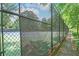Fenced tennis court with green surface, surrounded by mature trees, and a sidewalk at 22 The Prado Ne, Atlanta, GA 30309