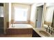 Bathroom featuring soaking tub with tile surround, granite vanity, tile flooring and natural light at 5122 Micaela Way, Duluth, GA 30096