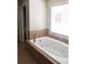 Relaxing bathroom with a jetted tub with tile surround and a large window at 5122 Micaela Way, Duluth, GA 30096