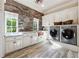 Bright laundry room with white cabinets, brick accent wall, and modern washer/dryer at 811 Flathead Pass, Suwanee, GA 30024