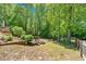Well maintained backyard featuring mature trees, fire pit, and lush landscaping at 4309 Milford Pl, Hoschton, GA 30548