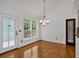 Cozy dining room features a modern light fixture, hardwood floors, and a large window with a view of the backyard at 4309 Milford Pl, Hoschton, GA 30548