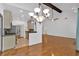 Open-concept living area with hardwood floors, exposed beam, light fixture, and seamless transition to the modern kitchen at 4309 Milford Pl, Hoschton, GA 30548