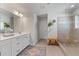 This is a bathroom featuring double sinks, a walk-in shower with a glass door, a bench, and a large decorative rug at 6070 Arbor Green Cir, Sugar Hill, GA 30518