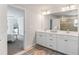 This is a bathroom that features double sinks, white cabinetry, a large mirror and a glass-enclosed shower at 6070 Arbor Green Cir, Sugar Hill, GA 30518