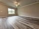 Large living room with wood-look floors, neutral paint, ceiling fan, and large window at 1217 Fern Ridge Ct # 16, Norcross, GA 30093