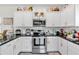 A bright kitchen offers white cabinets, stainless appliances, black countertops, and decor for a homey feeling at 173 Bramlett Ridge Dr, Dallas, GA 30157
