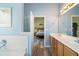 Bathroom featuring a double sink vanity adjacent to the bedroom and a tub at 7430 Valley Landing Ct, Cumming, GA 30041