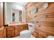 Rustic bathroom featuring wood paneling, wooden floors and updated sink and toilet at 1326 Janmar Rd, Snellville, GA 30078
