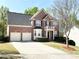 Charming two-story brick home with a two-car garage, black shutters, and well-manicured landscaping at 2585 Chandler Grove Dr, Buford, GA 30519