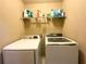 Convenient laundry room featuring modern washer and dryer units, plus shelving for storage at 2585 Chandler Grove Dr, Buford, GA 30519